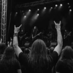 Black and white photo of a festival crowd at Wacken Open Air, with raised hands and heavy metal atmosphere.